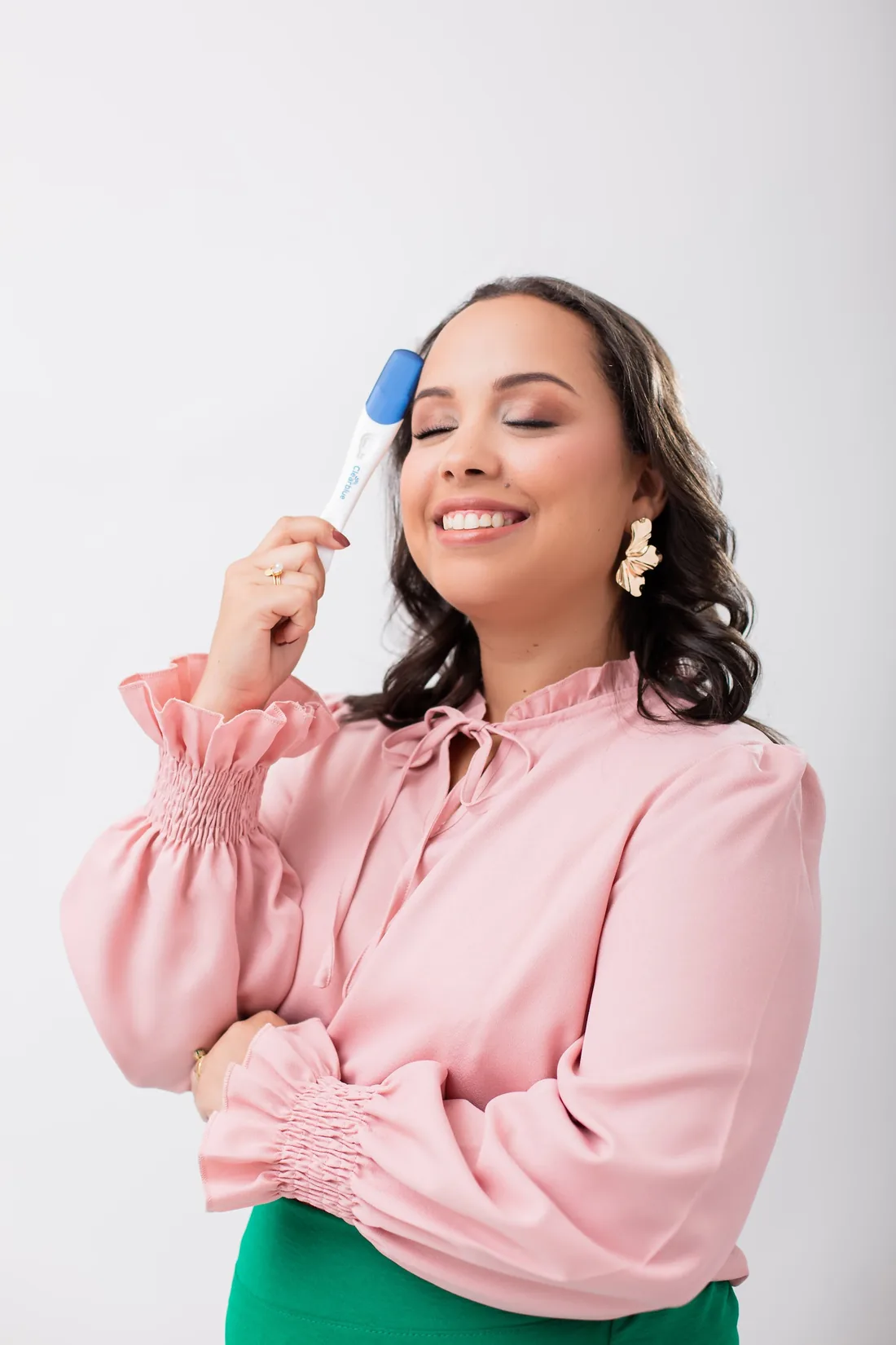 Idma Socha sorrindo de olhos fechados, segurando um teste de gravidez